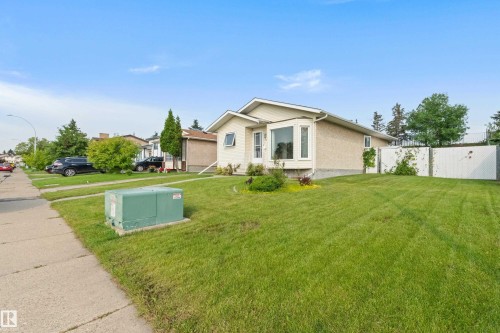 Stucco exterior with a bay window, a concrete sidewalk, and a green lawn - 14538 37 Street Nw, Edmonton, AB 