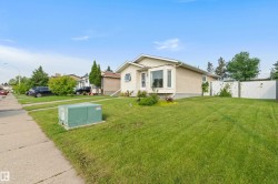 Stucco exterior with a bay window, a concrete sidewalk, and a green lawn - 