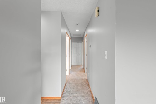 Hallway featuring recessed lighting, light gray wall paint, and wood trim around doorways - 14538 37 Street Nw, Edmonton, AB 