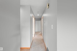 Hallway featuring recessed lighting, light gray wall paint, and wood trim around doorways - 