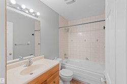 Bathroom featuring a full-width vanity mirror, a vanity with a drop-in sink, a standard toilet, and a tiled shower-over-tub combination with a chrome shower rod - 