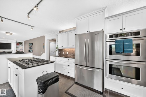 White cabinetry, stainless steel appliances, dark countertops, tiled flooring, and a tiled backsplash - #38 24512 Sturgeon Rd, Rural Sturgeon County, AB 
