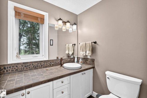 White vanity with shaker-style cabinetry, a white vessel sink, and a bronze-finish faucet - #38 24512 Sturgeon Rd, Rural Sturgeon County, AB 
