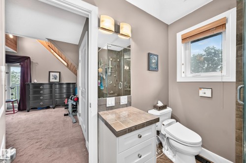 Bathroom featuring a tiled vanity countertop, wall-mounted light fixture, and glass-enclosed shower - #38 24512 Sturgeon Rd, Rural Sturgeon County, AB 