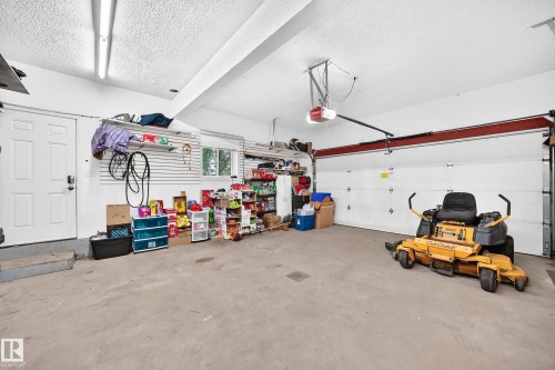 Spacious garage featuring a concrete floor, overhead fluorescent lighting, and an automatic garage door opener - #38 24512 Sturgeon Rd, Rural Sturgeon County, AB 