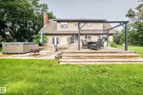 Expansive backyard featuring a composite wood deck with multiple steps, a hot tub, and a pergola structure - #38 24512 Sturgeon Rd, Rural Sturgeon County, AB 