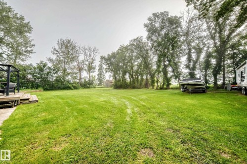 Expansive green lawn with mature trees and a wooden deck - #38 24512 Sturgeon Rd, Rural Sturgeon County, AB 