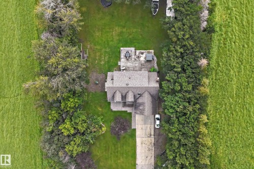 Spacious property featuring expansive green lawns, mature perimeter trees, a multi-gabled roofline, a concrete driveway, and an outdoor patio with hardscaping - #38 24512 Sturgeon Rd, Rural Sturgeon County, AB 