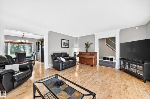 Spacious living area featuring wood-finish flooring, light gray walls, and crown molding - #38 24512 Sturgeon Rd, Rural Sturgeon County, AB 