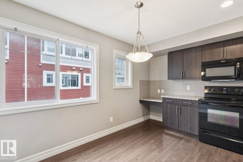 Wood-finish flooring, recessed ceiling lighting, pendant light fixture, built-in cabinetry, and integrated countertop space - 5409 3 Avenue Sw, Edmonton, AB - Indoor Photo Showing Kitchen
