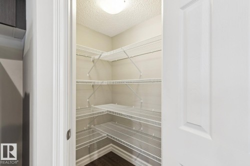 Corner shelving system, interior lighting, and dark wood-finish flooring - 5409 3 Avenue Sw, Edmonton, AB - Indoor With Storage