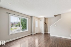 Hardwood-finish flooring, recessed ceiling lighting, window with grid panes, white trim, and a white interior door - 