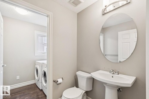Pedestal sink with chrome fixtures, oval mirror, and overhead vanity lighting - 5409 3 Avenue Sw, Edmonton, AB - Indoor