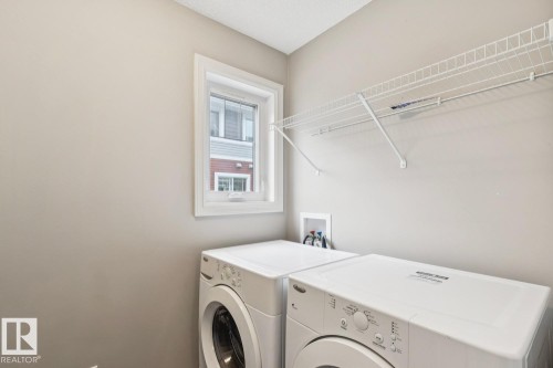 Dedicated laundry space featuring a window, built-in wire shelving, and appliance hookups - 5409 3 Avenue Sw, Edmonton, AB - Indoor Photo Showing Laundry Room