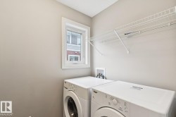 Dedicated laundry space featuring a window, built-in wire shelving, and appliance hookups - 