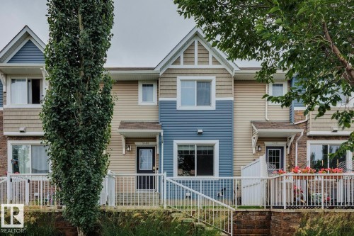 Multi-level townhome exterior featuring blue and tan siding, white railings, and an individual entrance - 5409 3 Avenue Sw, Edmonton, AB - Outdoor With Facade