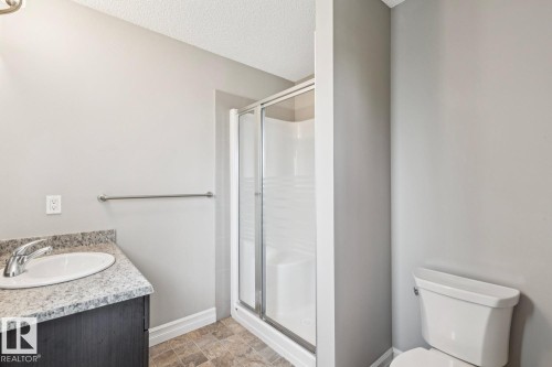Vanity with granite-style countertop and integrated sink, chrome faucet, glass-enclosed shower, and neutral wall paint - 5409 3 Avenue Sw, Edmonton, AB - Indoor Photo Showing Bathroom
