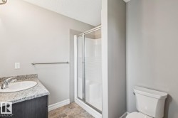 Vanity with granite-style countertop and integrated sink, chrome faucet, glass-enclosed shower, and neutral wall paint - 