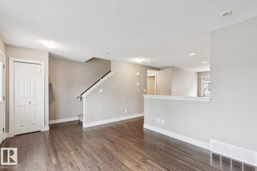 Wood-finish flooring, staircase with white railing, built-in shelving, white bi-fold closet doors, and recessed lighting - 5409 3 Avenue Sw, Edmonton, AB - Indoor Photo Showing Other Room
