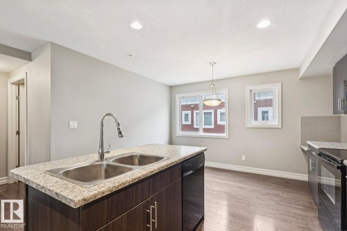 Kitchen island featuring a double basin stainless steel sink and a gooseneck faucet - 5409 3 Avenue Sw, Edmonton, AB - Indoor Photo Showing Kitchen With Double Sink