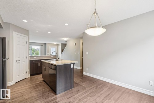 Kitchen island with built-in sink and dishwasher, wood-finish flooring, recessed lighting, and a contemporary pendant light fixture - 5409 3 Avenue Sw, Edmonton, AB - Indoor Photo Showing Kitchen