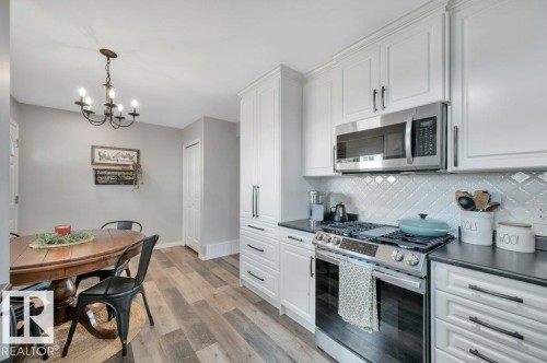 White shaker cabinetry, dark countertops, stainless steel appliances, decorative tile backsplash, and vinyl plank flooring - #138 5231 51 St, Bon Accord, AB - Indoor Photo Showing Kitchen With Upgraded Kitchen