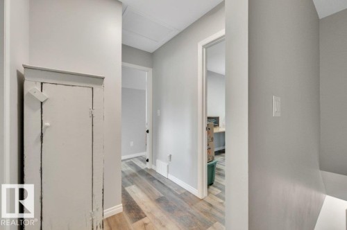 Wood-finish flooring throughout the hallway, light gray wall paint, and white trim - #138 5231 51 St, Bon Accord, AB - Indoor Photo Showing Other Room