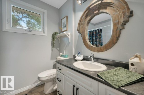 White vanity with dark hardware, dark countertop, and an oval undermount sink - #138 5231 51 St, Bon Accord, AB - Indoor Photo Showing Bathroom