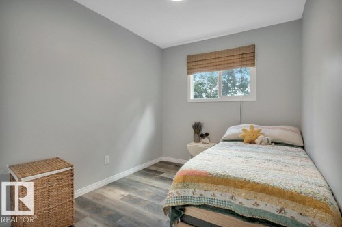 Gray walls with white trim, vinyl plank flooring, and a window with a woven shade - #138 5231 51 St, Bon Accord, AB - Indoor Photo Showing Bedroom