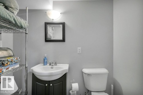 Wall-mounted vanity light, framed mirror, pedestal sink with cabinet storage, and toilet - #138 5231 51 St, Bon Accord, AB - Indoor Photo Showing Bathroom