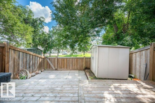 Expansive wood deck with a privacy fence, complemented by a paver patio and a functional storage shed - #138 5231 51 St, Bon Accord, AB - Outdoor With Deck Patio Veranda