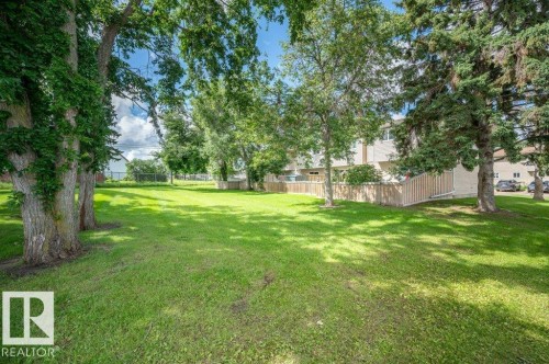 Expansive green space featuring mature trees and a partial wood fence - #138 5231 51 St, Bon Accord, AB - Outdoor