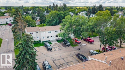 Two-story residential building with light-colored siding, a brown shingle roof, and multiple windows - #138 5231 51 St, Bon Accord, AB - Outdoor With View