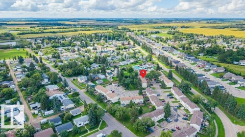 Aerial perspective showcasing a residential community with abundant mature trees and expansive green spaces - #138 5231 51 St, Bon Accord, AB - Outdoor With View