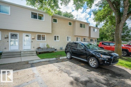 Townhouse-style multi-unit building with light-colored siding and stucco exterior, individual entry doors, and concrete steps - #138 5231 51 St, Bon Accord, AB - Outdoor