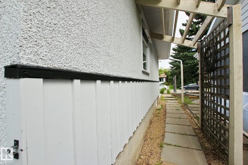 Stucco exterior with a painted wood privacy screen and concrete paver pathway - 5712 113B Street Nw, Edmonton, AB - Outdoor