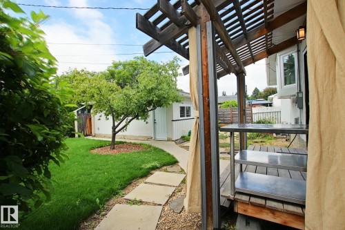 Outdoor pergola structure, wood deck, built-in shelving, stone pathway, and a detached white-sided building with a door - 5712 113B Street Nw, Edmonton, AB - Outdoor With Exterior