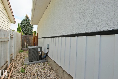Stucco exterior with vertical paneling, gravel ground cover, and a concrete pad - 5712 113B Street Nw, Edmonton, AB - Outdoor With Exterior