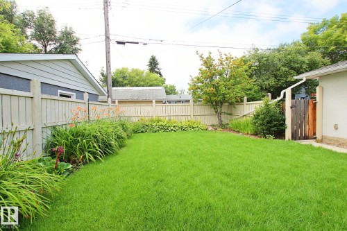 Expansive backyard with a manicured lawn, established garden beds, and perimeter fencing - 5712 113B Street Nw, Edmonton, AB - Outdoor