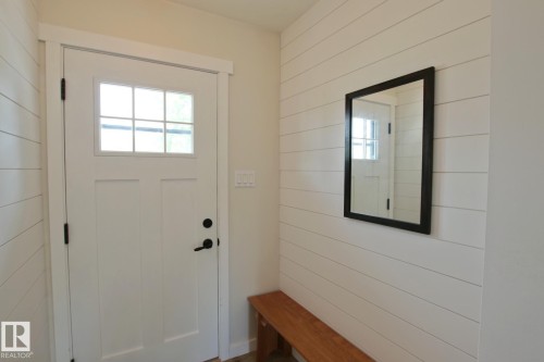 White entry door with divided light window, shiplap wall paneling, and matte black hardware - 5712 113B Street Nw, Edmonton, AB - Indoor Photo Showing Other Room
