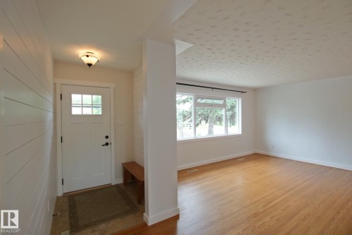 Entryway featuring white shiplap accent walls, a white paneled door with windowpanes, and a flush-mount ceiling light - 5712 113B Street Nw, Edmonton, AB - Indoor Photo Showing Other Room