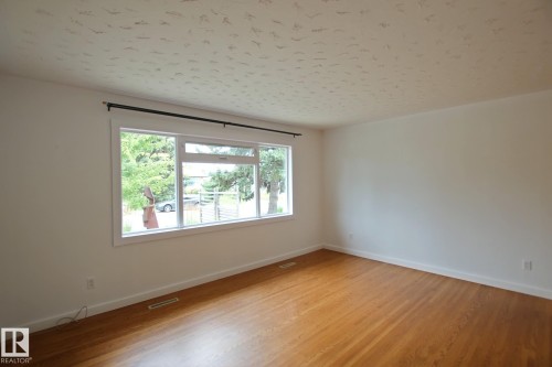 Hardwood flooring, expansive window, white walls, white trim, and a textured ceiling - 5712 113B Street Nw, Edmonton, AB - Indoor Photo Showing Other Room