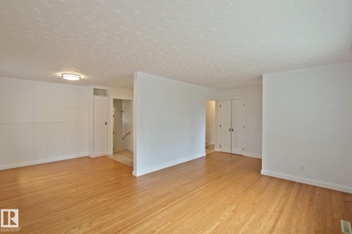 Hardwood flooring throughout, built-in storage cabinetry, flush-mount ceiling light, white wall finishes, and white trim - 5712 113B Street Nw, Edmonton, AB - Indoor Photo Showing Other Room