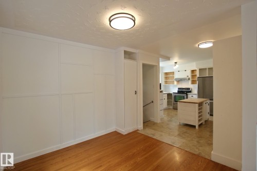 Hardwood flooring, paneled wall detail, recessed lighting, kitchen with stainless steel appliances, and a central island with wood countertop - 5712 113B Street Nw, Edmonton, AB - Indoor Photo Showing Other Room