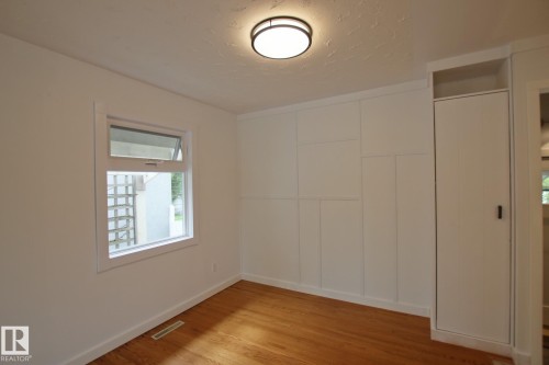 Wood-finish flooring, built-in storage, casement window, ceiling-mounted light fixture, and paneled accent wall - 5712 113B Street Nw, Edmonton, AB - Indoor Photo Showing Other Room