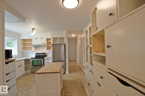 Kitchen featuring white cabinetry, wood-finish countertops, subway tile backsplash, stainless steel appliances, and a central island with natural wood top - 5712 113B Street Nw, Edmonton, AB - Indoor Photo Showing Kitchen