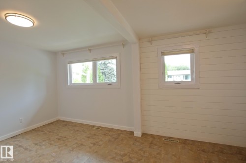 Interior room with two windows, a white shiplap accent wall, and a flush-mount ceiling light - 5712 113B Street Nw, Edmonton, AB - Indoor Photo Showing Other Room