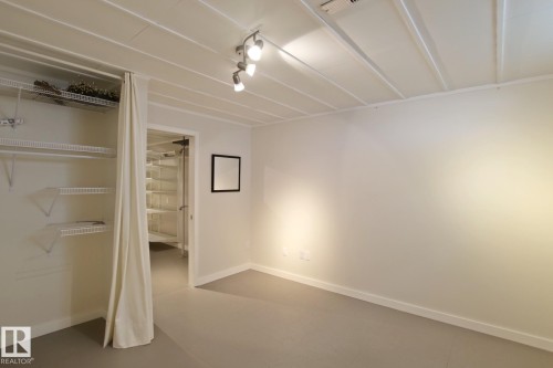 Track lighting fixture, wire shelving system, painted concrete flooring, and ceiling with exposed joists - 5712 113B Street Nw, Edmonton, AB - Indoor