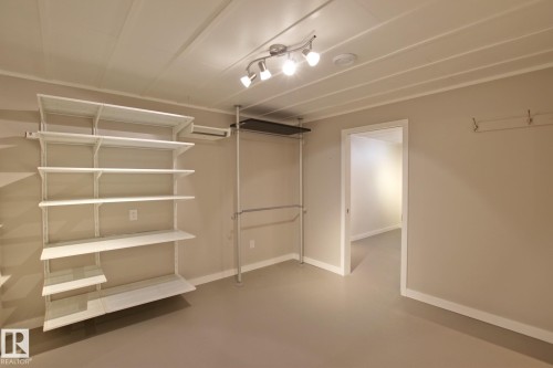 Track lighting fixture, white trim, light neutral wall color, built-in shelving, and a built-in clothing rack - 5712 113B Street Nw, Edmonton, AB - Indoor Photo Showing Other Room