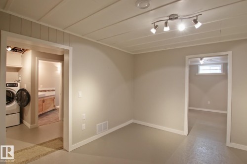 Neutral wall color, track lighting fixture, laundry area with built-in cabinetry, and a bathroom with a vessel sink vanity - 5712 113B Street Nw, Edmonton, AB - Indoor